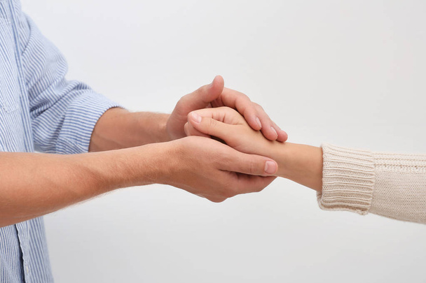 Man holding woman's hand on light background. Concept of support and help - Fotoğraf, Görsel