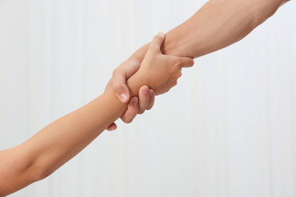 People holding hands together on light background. Concept of support and help - Φωτογραφία, εικόνα