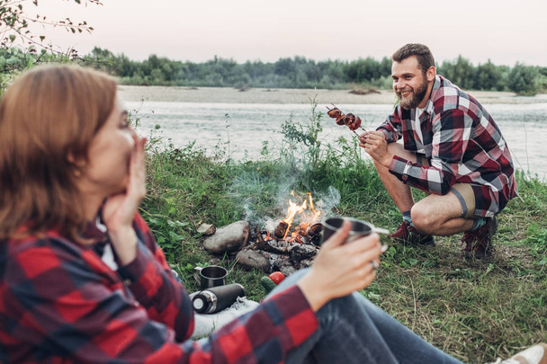 Šťastný mladý pár sedí u ohně pikniku v přírodě - Fotografie, Obrázek