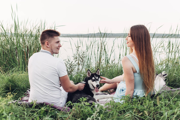 Молодая пара развлекается со своей собакой Хаски на Сансет Вне города на природе
 - Фото, изображение