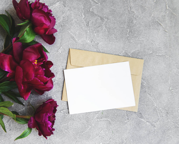 招待カード、クラフト封筒、石の背景にピンクの牡丹の花 - 写真・画像