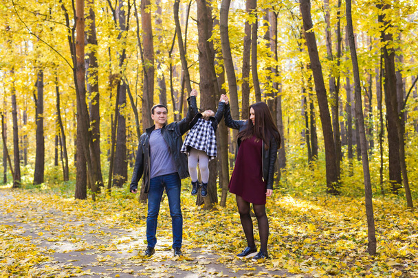 People, family and leisure concept - happy family with daughter walking in autumn park - Photo, Image