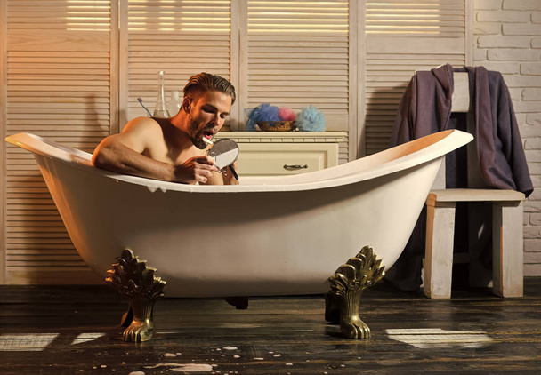 Muscular man shaving beard in bathroom - Valokuva, kuva
