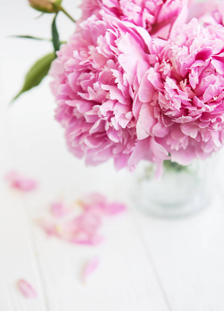 Vase mit rosa Pfingstrosenblüten auf weißem Holztisch - Foto, Bild