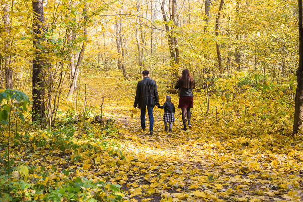 personnes, concept de famille et de loisirs - famille avec une jeune fille marchant dans le parc d'automne, vue arrière
 - Photo, image