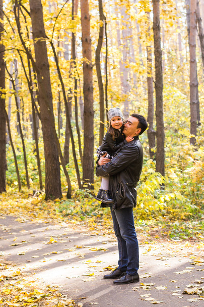 Сім'я, осінь, концепція людей - батько і дочка гуляють в осінньому парку. Дочка на руках тата
 - Фото, зображення