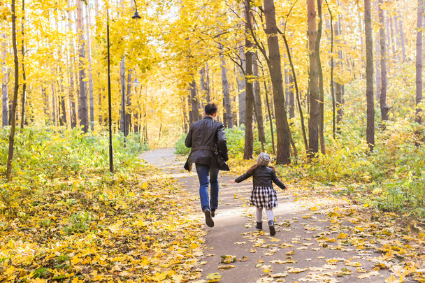 Family, autumn, people concept - father and daughter walking in autumn park - Photo, Image