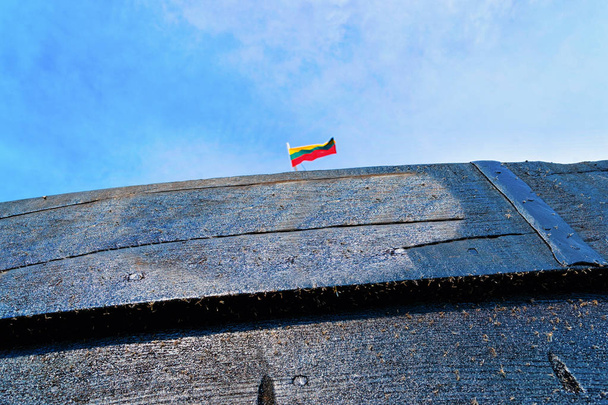 Фрагмент деревянного судна в курортном городке Нида близ Клайпеды в Неринге на Балтийском море на Куршской косе в Литве. Флаг Литвы
 - Фото, изображение