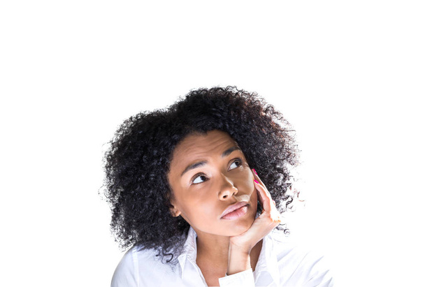 Isolated portrait of thoughtful young african american woman with curly black hair looking up with her hand on the chin. Concept of decision making - Valokuva, kuva