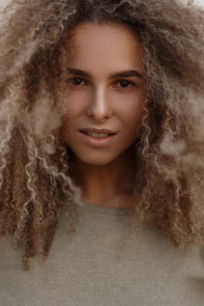 Natural close-up portrait of a beautiful young model curly girl with brown eyes in a T-shirt outdoors. Woman model face - Zdjęcie, obraz