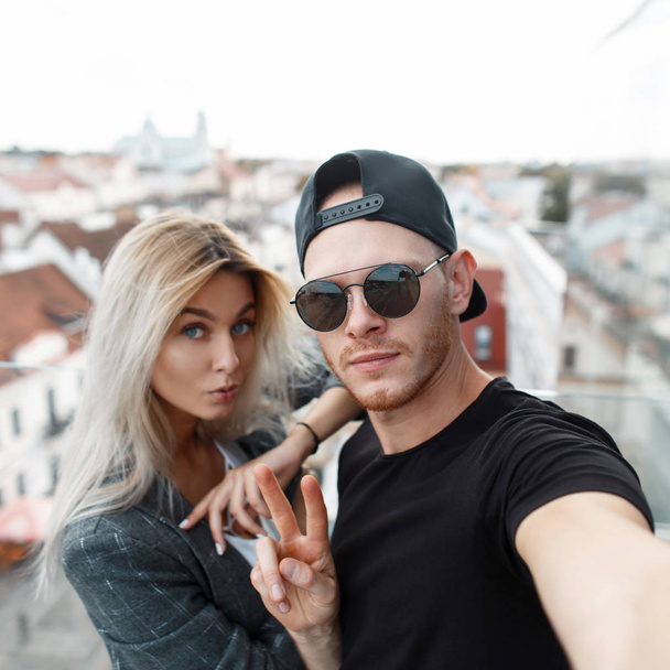 Стильная молодая пара путешествует по городу и делает селфи в городе на крыше
 - Фото, изображение