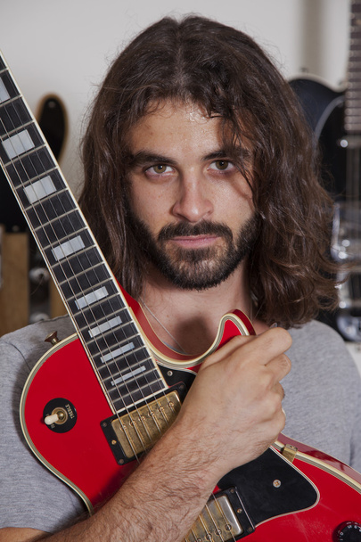 Portrait of serious young musician holding guitar - Φωτογραφία, εικόνα