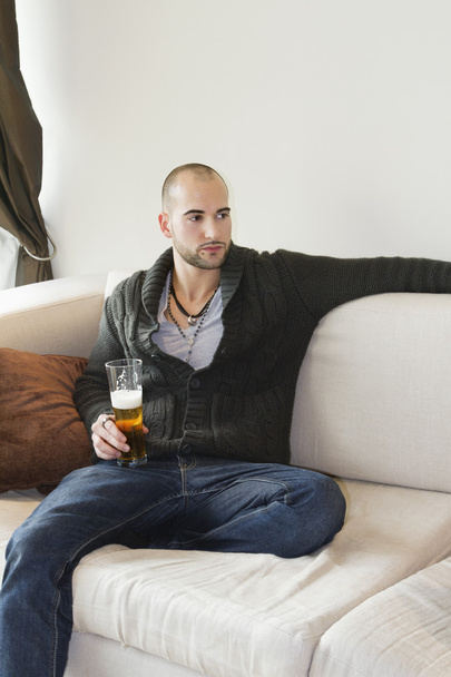 Young man sitting comfortably on sofa holding a drink - Photo, Image
