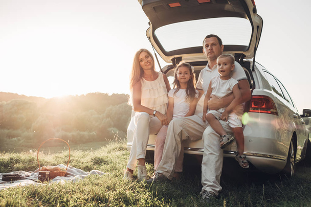 Adult couple with their little children having picnic in the Park Outside the City, Family Weekend Concept, Four People Enjoying Summer - Foto, Imagen