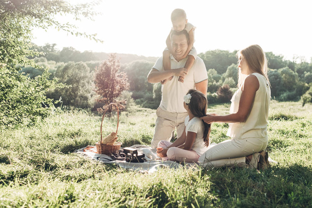 Casal adulto com seus filhos pequenos fazendo piquenique no Parque Fora da Cidade, Conceito de fim de semana de família, Quatro pessoas desfrutando do verão
 - Foto, Imagem