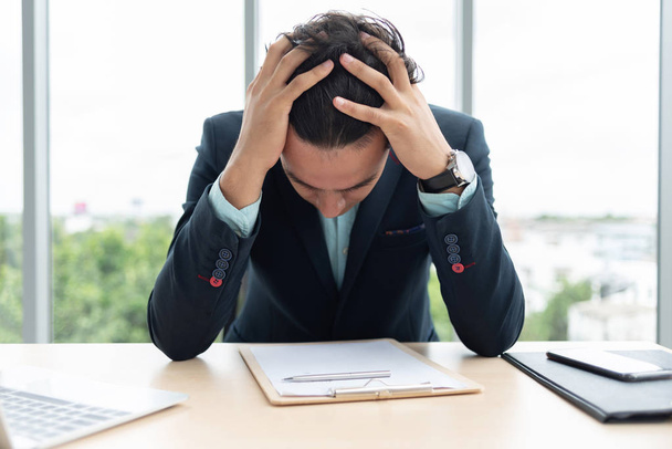 Stressato imprenditore sta tenendo la testa con le mani mentre lavora in ufficio
. - Foto, immagini