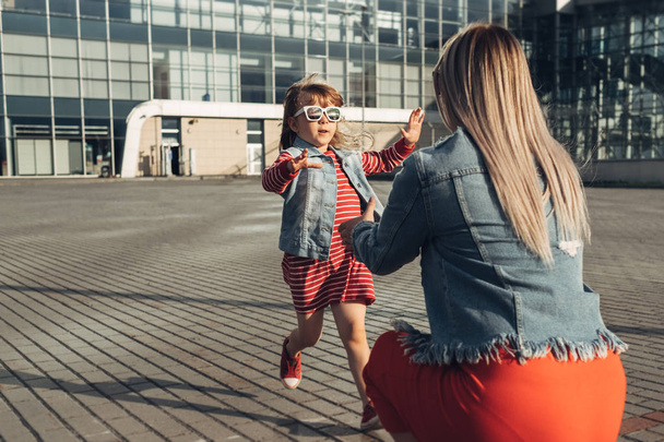 Beautiful Young Mother with Small Stylish Daughter Walks Through City - Photo, Image
