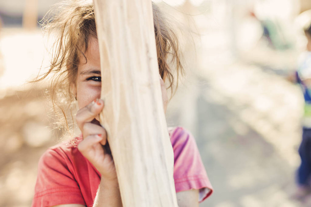 The girl hides behind a wooden pole - Фото, изображение