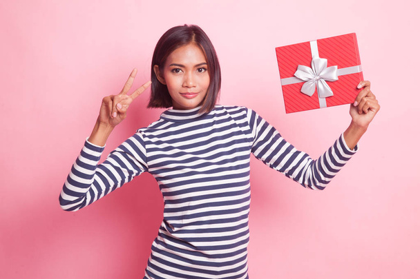 Asian woman show victory sign with a gift box on pink background - Foto, Imagem