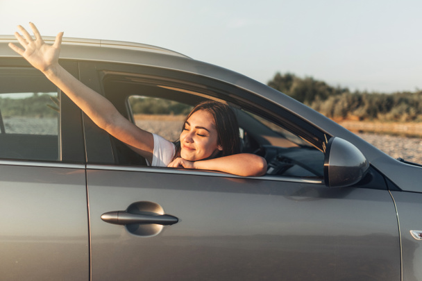 Mujer feliz en viaje por carretera en el atardecer en SUV Car
 - Foto, imagen