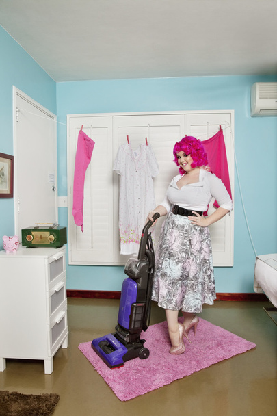 Portrait of a happy young woman vacuuming carpet - Foto, Imagen