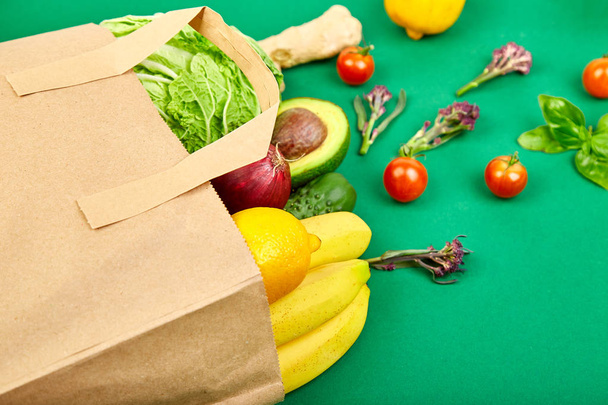  Grocering έννοια. Γεμάτη χαρτοσακούλα των διαφορετικών φρούτων και λαχανικών, υλικά για υγιεινό μαγείρεμα σε ένα χρώμα φόντου. υγιεινά τρόφιμα. Τροφίμων διατροφή ή vegan, χορτοφάγος. Το Top view. Επίπεδη θέσει.  - Φωτογραφία, εικόνα