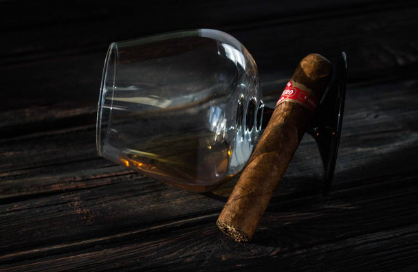 Glass of brandy and cuban cigar on an old wooden table. - Φωτογραφία, εικόνα