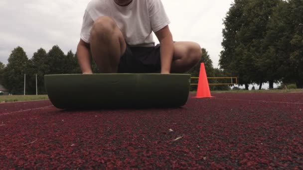 Άνθρωπος με γυμναστήριο mat στο γήπεδο - Πλάνα, βίντεο