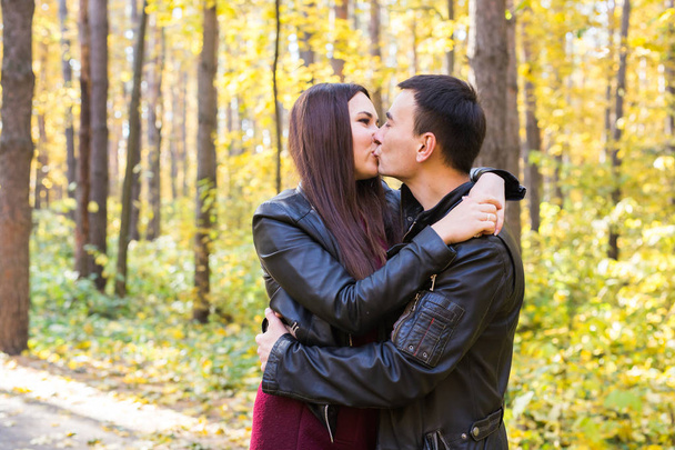 愛、関係、家族や人々 のコンセプト - 秋の公園で妻にキスをする男性 - 写真・画像