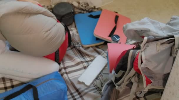 A woman tourist collects things in a backpack in the kitchen of the house and prepares for a trip - 映像、動画