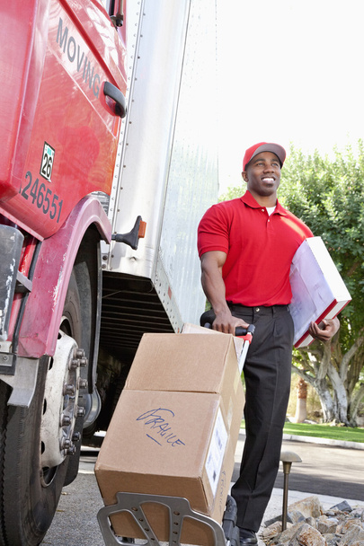 młody Afroamerykanin mężczyzna stojący z pakietów w pobliżu ciężarówka dostawcza - Zdjęcie, obraz