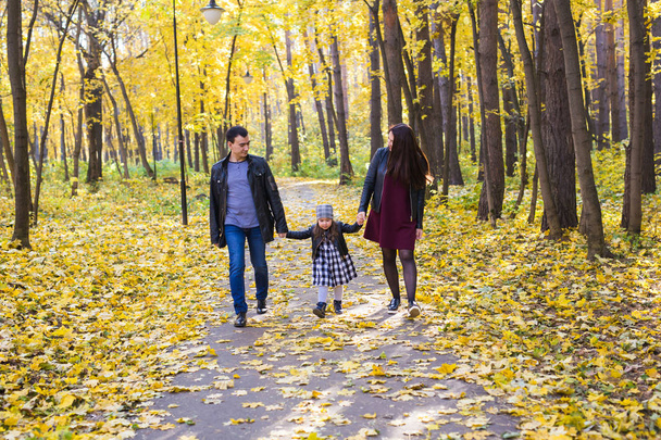 people, family and leisure concept - family with a young daughter walking in autumn park - Photo, Image