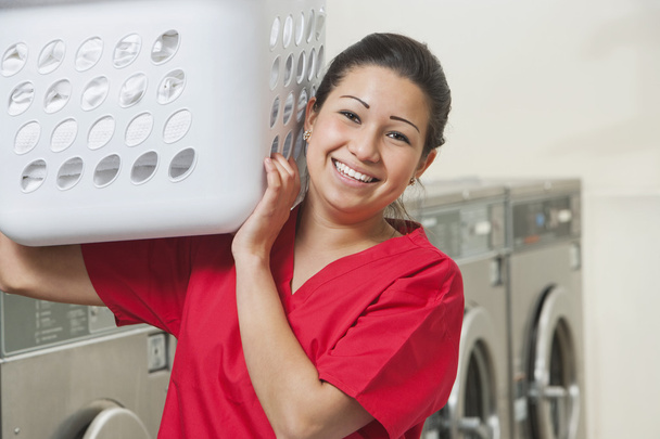 Portrait of a happy female employee carrying laundry basket - Photo, image