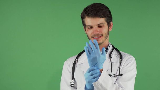 Όμορφος γενειοφόρος αρσενικό γιατρό βάζοντας σε Ιατρικά γάντια - Φωτογραφία, εικόνα