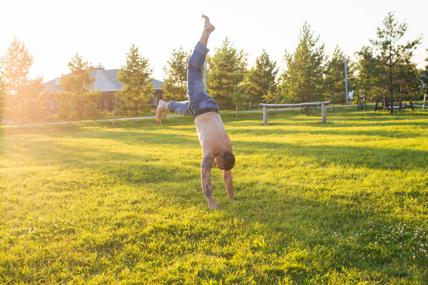 Yoga, fitness and healthy lifestyle concept - man doing a handstand on summer nature - Photo, Image