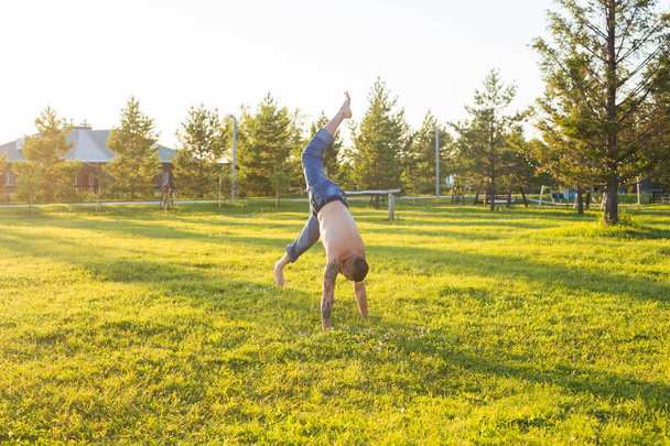 Γιόγκα, γυμναστήριο και υγιεινού τρόπου ζωής έννοια - ο άνθρωπος που κάνει ένα handstand στο καλοκαίρι φύση - Φωτογραφία, εικόνα