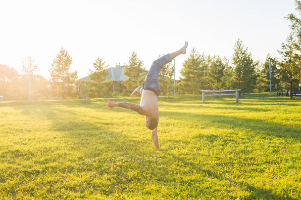 Γιόγκα, γυμναστήριο και υγιεινού τρόπου ζωής έννοια - ο άνθρωπος που κάνει ένα handstand στο καλοκαίρι φύση - Φωτογραφία, εικόνα