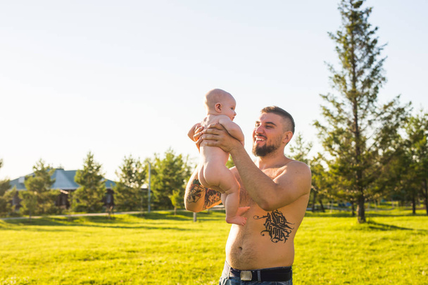 Happy father holding baby son on nature. Concept of happy family, fathers day and child. - Photo, Image