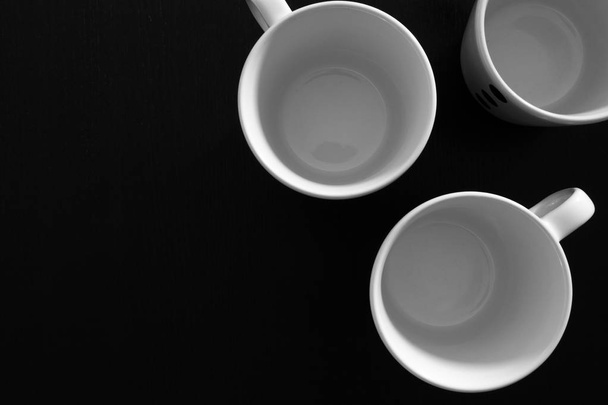 Пустые белые чашки на черном деревянном столе. Кухонные инструменты закрываются
 - Фото, изображение