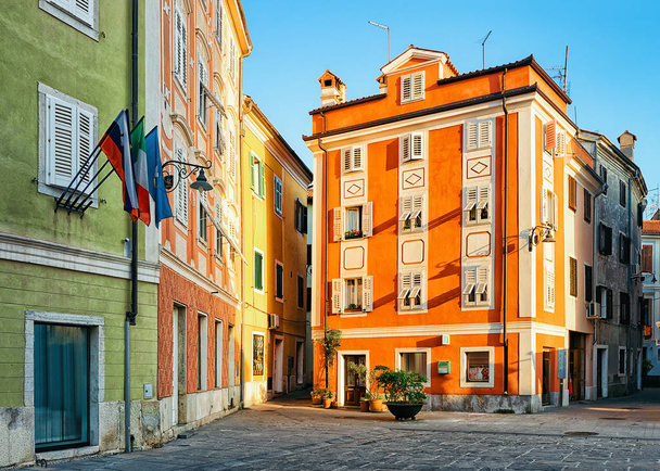 Bandeiras no edifício na praça histórica da cidade velha de Izola, Eslovênia
 - Foto, Imagem