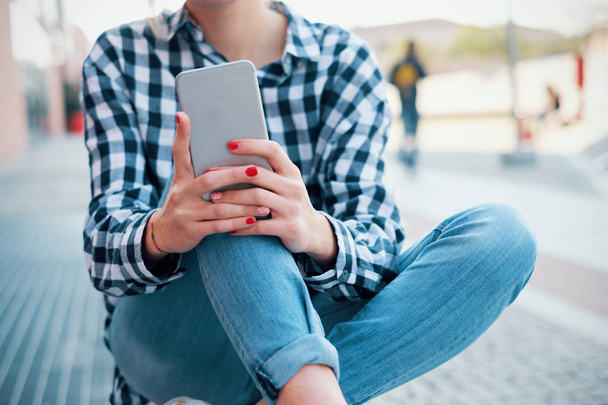 junges Millennial-Mädchen chattet und nutzt Smartphone in der Stadt - Foto, Bild