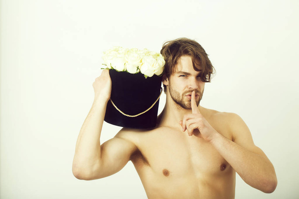 man showing silence finger gesture with roses in box - 写真・画像