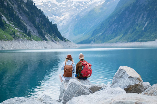 Travelers couple look at the mountain lake. Travel and active life concept with team. Adventure and travel in the mountains region in the Austria - Photo, Image