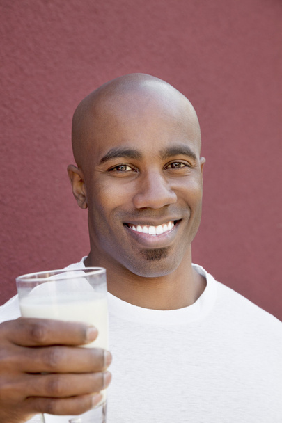 Portrait of a happy young man with milk glass over colored background - Fotó, kép