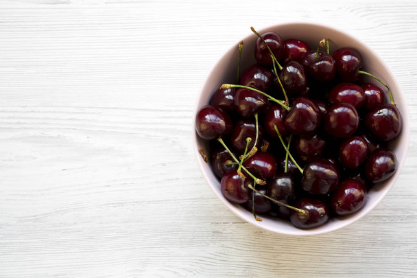 Full pink bowl of cherries, overhead view. Flat lay, top view, from above. Copy space. - Zdjęcie, obraz