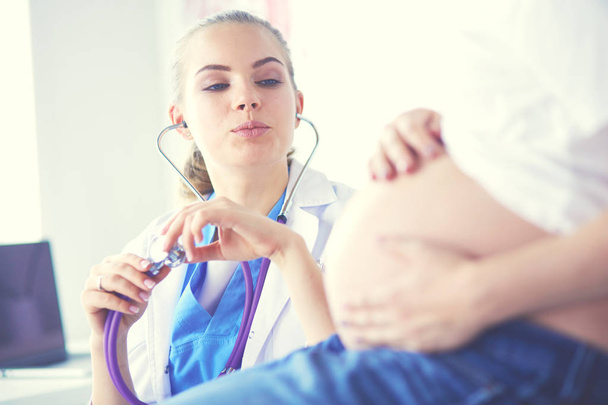 Doctora joven examinando a una mujer embarazada en la clínica. - Foto, imagen
