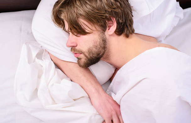 Guy lay under white bedclothes. Man unshaven handsome relaxing bed. Power napping may help you get through day. Have nap relax. Man sleepy drowsy unshaven bearded face covered blanket having nap - Foto, afbeelding
