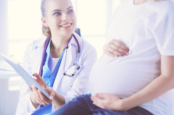Il medico sorridente mostra le immagini sulla compressa a una giovane donna incinta in ospedale. - Foto, immagini