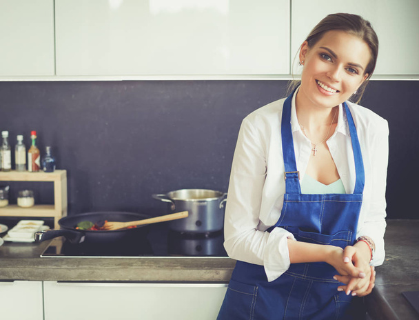 Portrait of young woman standing with arms crossed against kitchen background - Foto, Imagem