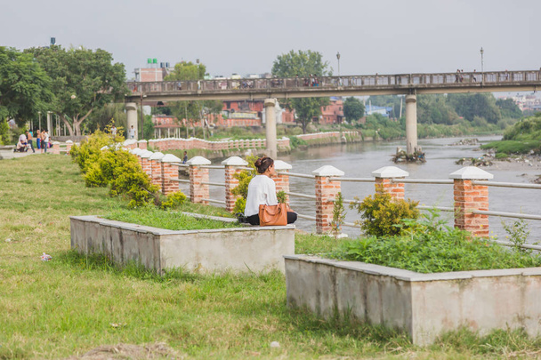 Kathmandu, Nepal - Sep 15,2018: czytanie dziewczynka A spokojne miejsce lub na Park, w pobliżu rzeki w mieście Katmandu. - Zdjęcie, obraz